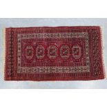 Tekke rug with red field with five octagons within multiple geometric and serrated edge borders, .