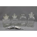 Four modern glass storage jars, tallest 35cm, three with domed lids, together with two metal scoops,