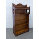 An early 20th century oak open bookcase , the wavy top with dentil and fan carved detail, with