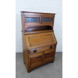An early 20th century oak secretaire cabinet, the cornice top above two lead glazed panel doors