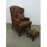 Wingback armchair and matching footstool with elephant design upholstery on short cabriole legs with