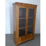 Walnut cabinet, cornice top above a pair of glazed doors with a shelved interior, with faux ivory