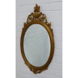 Reproduction gilt framed mirror with a classical urn surmount over an oval mirrored plate. 79 x 41cm