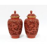 A pair of Chinese red cinnabar vases with covers, carved in high relief with dragons, (2) 19cm.
