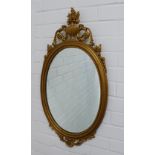 Reproduction faux gilt framed mirror with a classical urn surmount over an oval mirrored plate.