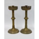 A pair of brass Gothic Revival candlesticks with stylised drip trays, raised on barley twist columns