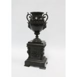 Classical bronze urn, with mask head handles and on a plinth base, 35cm