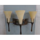 A pair of Chelsom bronze patinated metal wall sconce with three glass shades (one shade damaged)