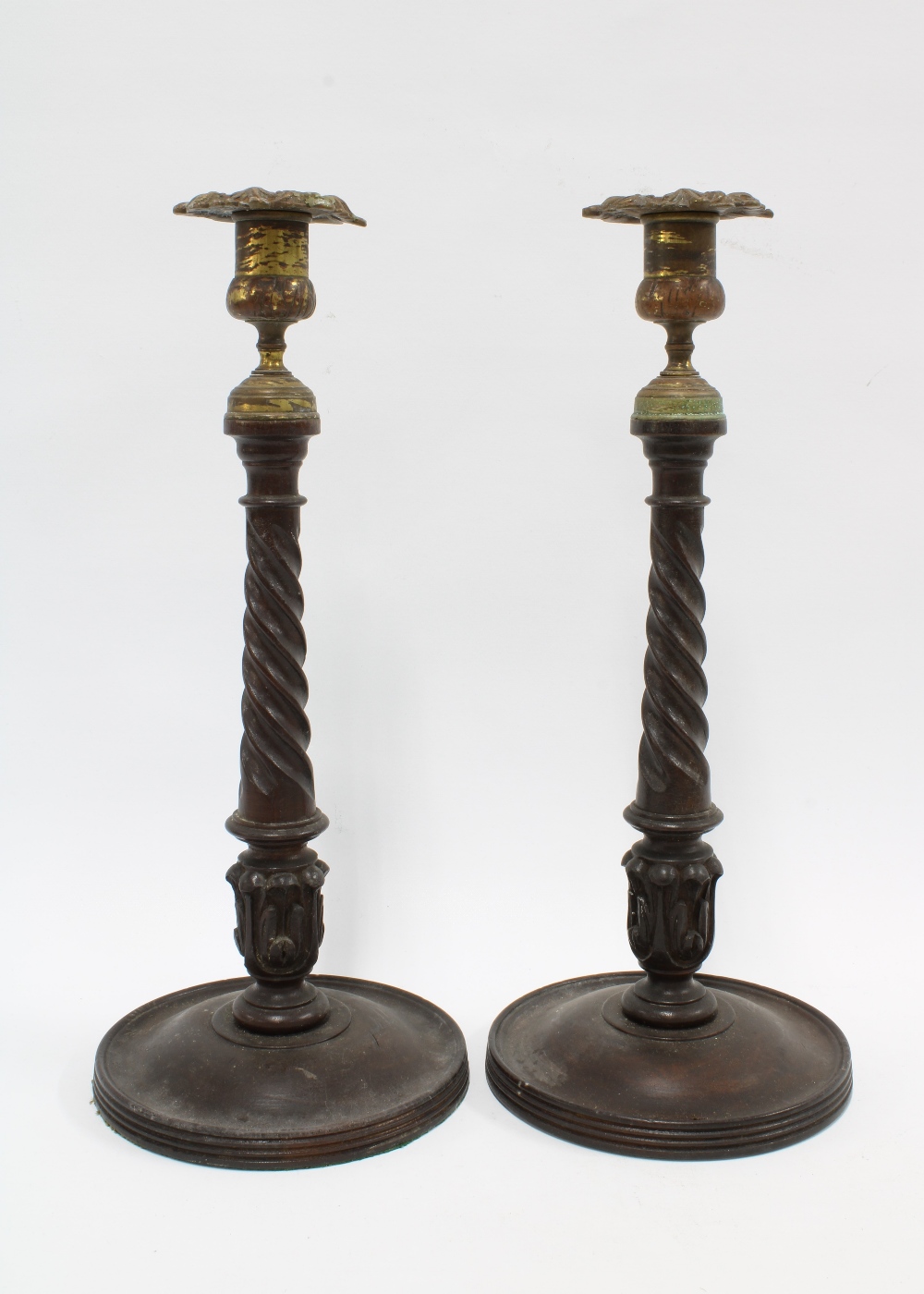 A pair of mahogany candlesticks with brass sconces, spiral stems and circular footrims, (2) 33cm.