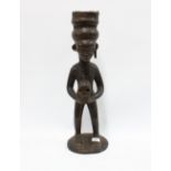 Congo, carved wooden African figure, modelled standing and holding a skull, 63cm high