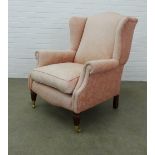 Country House wingback armchair with pink upholstery, mahogany legs with brass caps and castors,