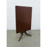 Mahogany tilt top table on a pedestal base with brass caps and castors, 94 x 71 x 68cm.
