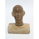 Small pottery Buddha head, on a wooden plinth, 11cm high overall