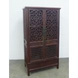 Late 19th century Chinese linden wood cabinet, the two doors with pierced panels, opening to