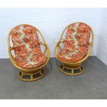 Pair of retro bamboo revolving swivel chairs, with loose orange pattern cushions, 76 x 98 x 60cm. (