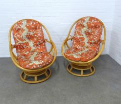 Pair of retro bamboo revolving swivel chairs, with loose orange pattern cushions, 76 x 98 x 60cm. (