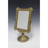 An ornate brass mirror with a rectangular glass plate on a circular footrim, 33cm high