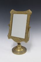 An ornate brass mirror with a rectangular glass plate on a circular footrim, 33cm high