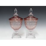 A pair of modern glass confiture stye jars with covers, pale pink with clear glass stem and foot,