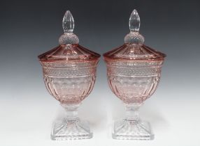 A pair of modern glass confiture stye jars with covers, pale pink with clear glass stem and foot,