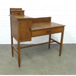 An Arts & Crafts oak dressing table, ledgeback , flanked by a jewel drawer and cupboard, raised on