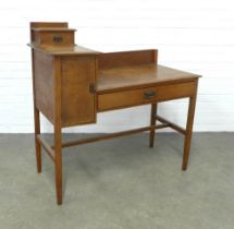 An Arts & Crafts oak dressing table, ledgeback , flanked by a jewel drawer and cupboard, raised on