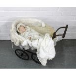 Doll's wicker pram with black metal wheels, together with a modern bisque head doll dressed in an