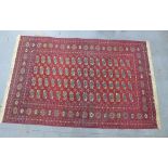 Bokhara carpet, red field with four rows of sixteen guls, 300 x 190cm.