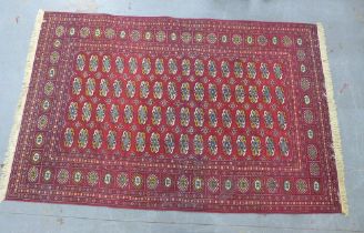 Bokhara carpet, red field with four rows of sixteen guls, 300 x 190cm.