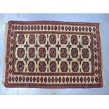 Bokhara style rug, beige field with three rows of seven guks, 175 x 128cm.