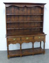 An oak Welsh style dresser, panelled back with three fixed long shelves above three short drawers