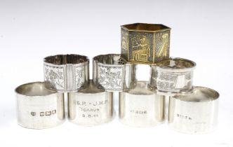 Seven silver napkin rings with various hallmarks and a brass napkin ring with Egyptian motifs, (8)