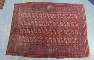 Bokhara type rug / carpet, worn red field with four rows of sixteen guls 296 x 22cm