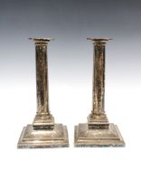 A pair of silver plate on copper candlesticks, engraved columns and standing on square stepped bases