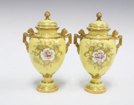 A pair of Coalport twin handled urn vases with covers, yellow ground with handpainted floral