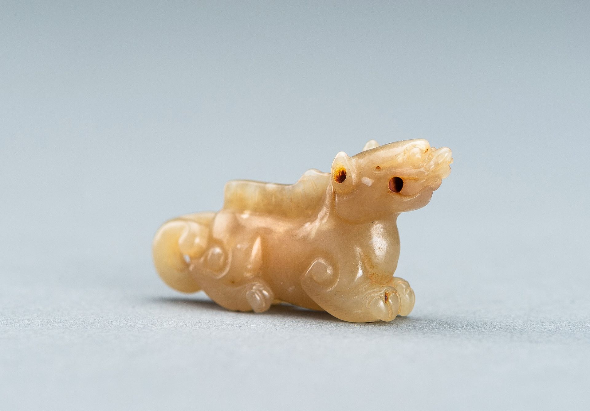 A PALE GREEN MINIATURE CARVING OF A LION, c. 1920s