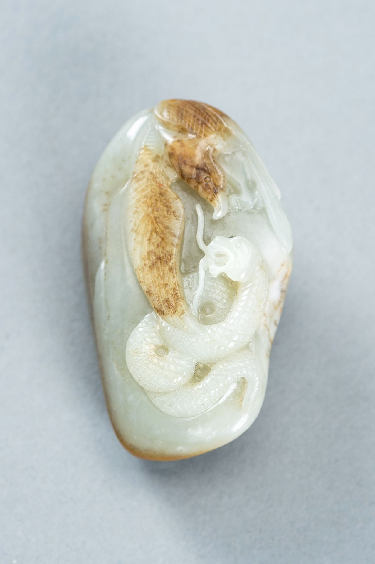 A CELADON AND RUSSET JADE 'EAGLE AND SNAKE' PENDANT, c. 1920s