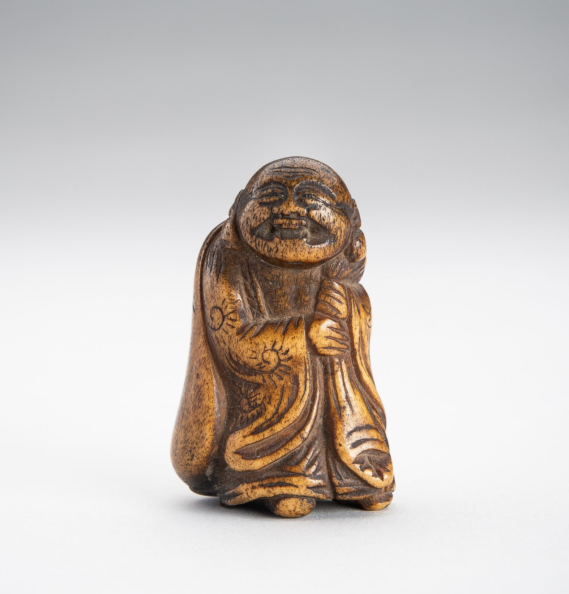 A STAG ANTLER NETSUKE OF HOTEI WITH HIS TREASURE BAG
