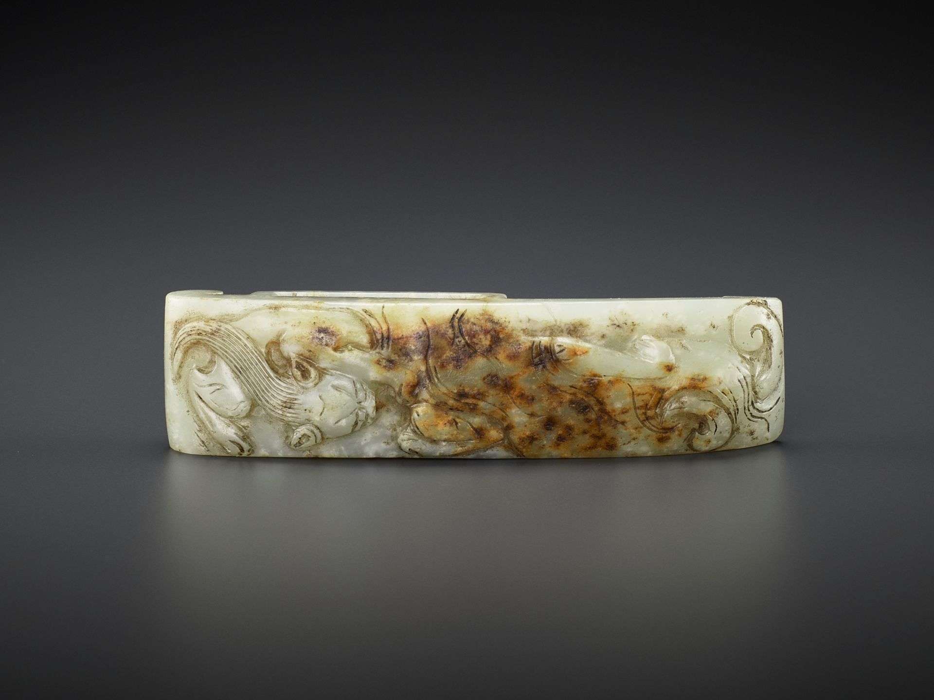 AN ARCHASITIC JADE SCABBARD SLIDE WITH DRAGON AMID CLOUDS, EARLY MING