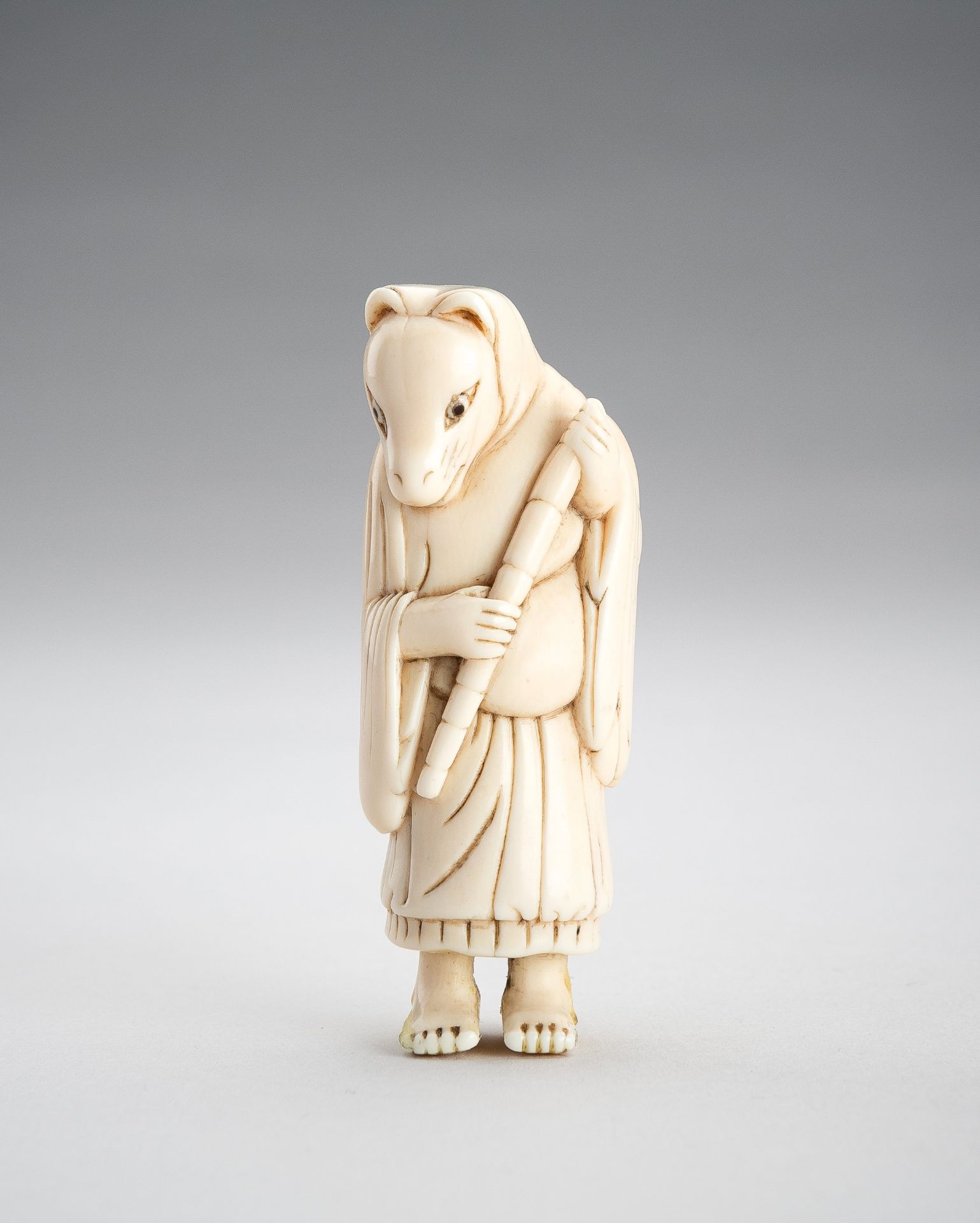 AN IVORY NETSUKE OF A FOX PRIEST