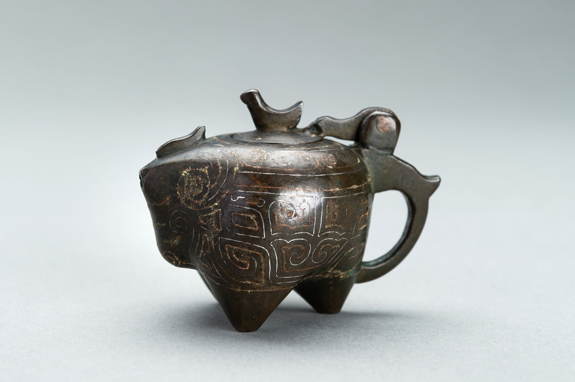 A SMALL COPPER AND SILVER INLAID BRONZE POURING TRIPOD VESSEL IN THE FORM OF AN ANIMAL, 17TH CENTURY
