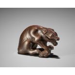 A FINE WOOD NETSUKE OF A WOLF WITH HAUNCH OF VENISON