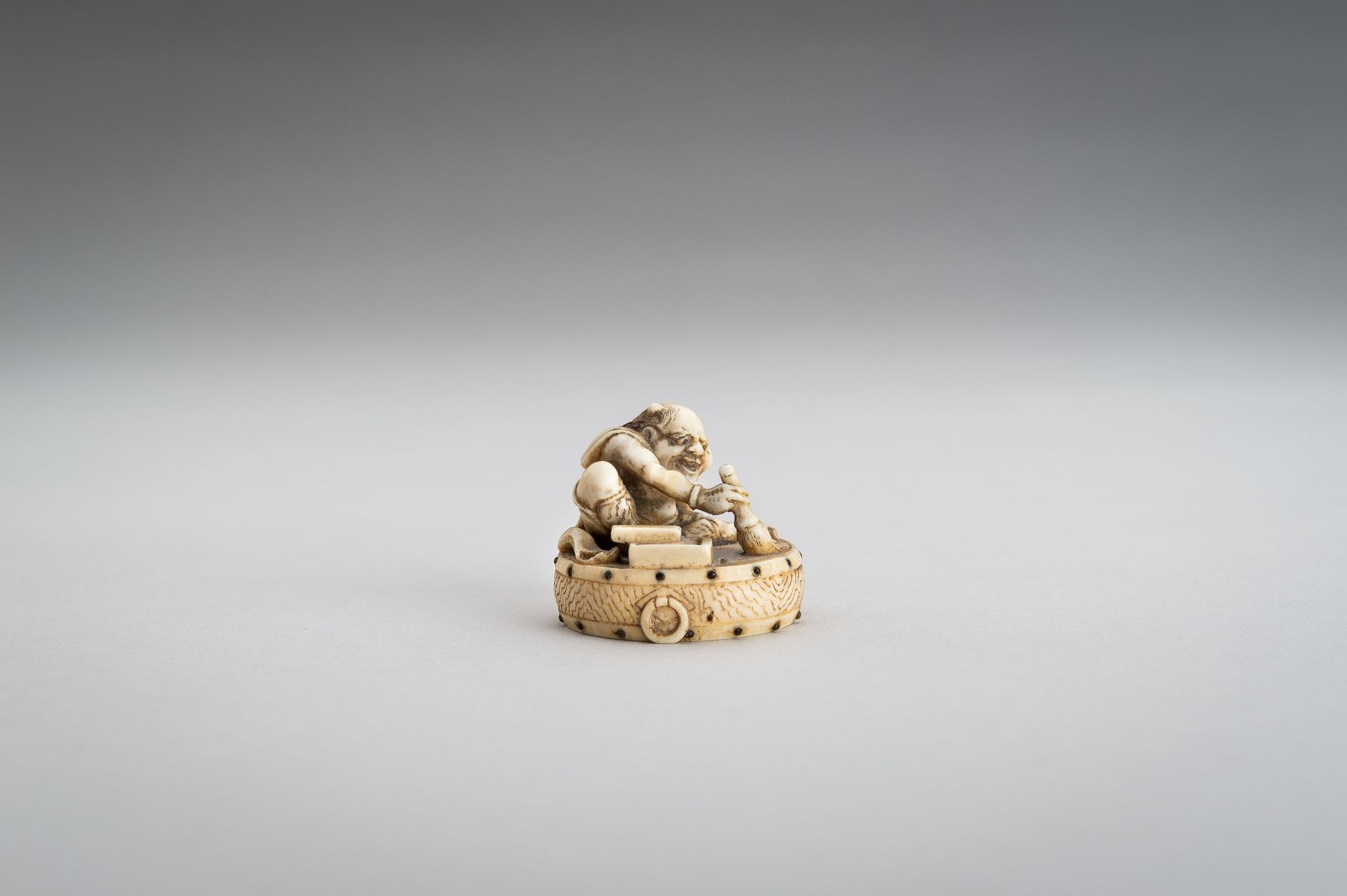 GYOKUSHU: AN IVORY NETSUKE OF AN ONI CLEANING A DRUM - Image 6 of 12