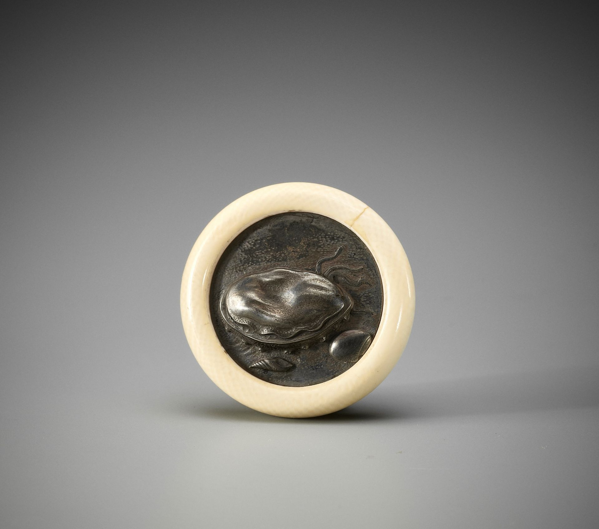 KIKUGAWA: AN IVORY AND SHIBUICHI KAGAMIBUTA NETSUKE WITH SHELLS