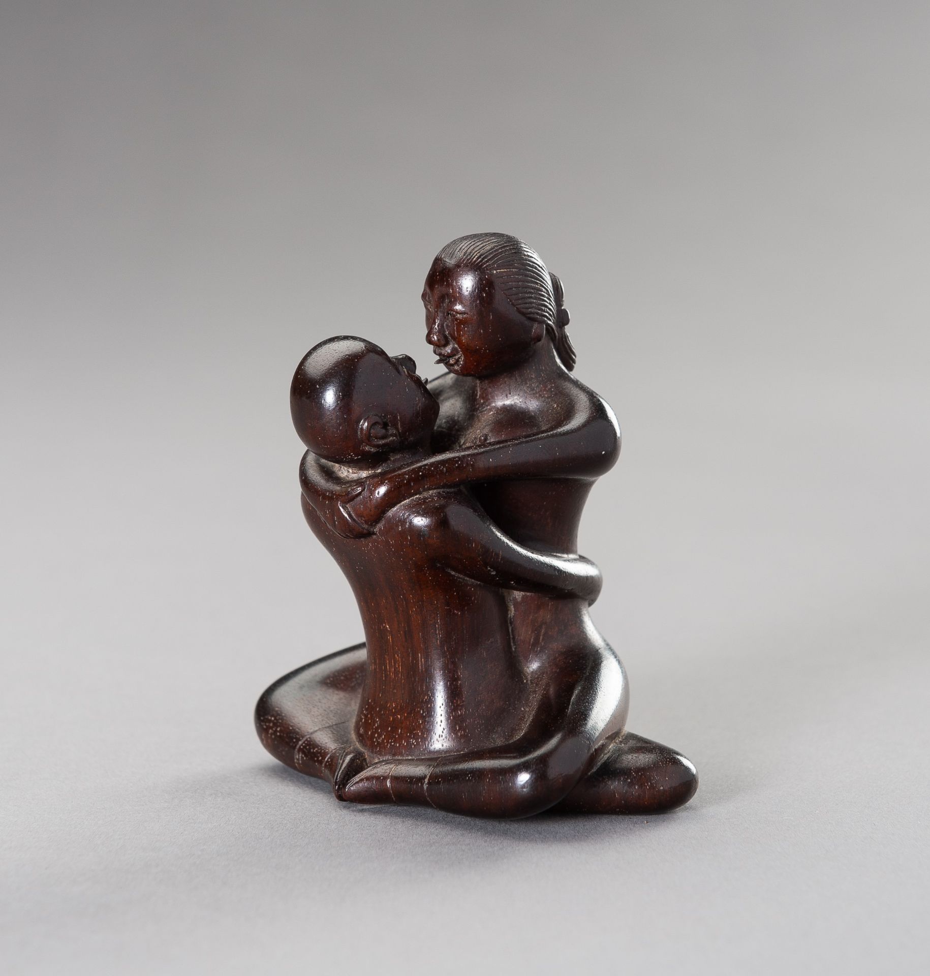 A ZITAN WOOD FIGURE OF A COUPLE IN EROTIC EMBRACE