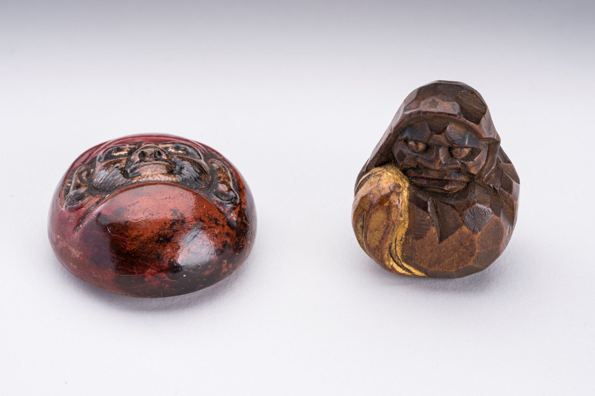 A HIDA SCHOOL WOOD NETSUKE AND A CERAMIC NETSUKE OF DARUMA