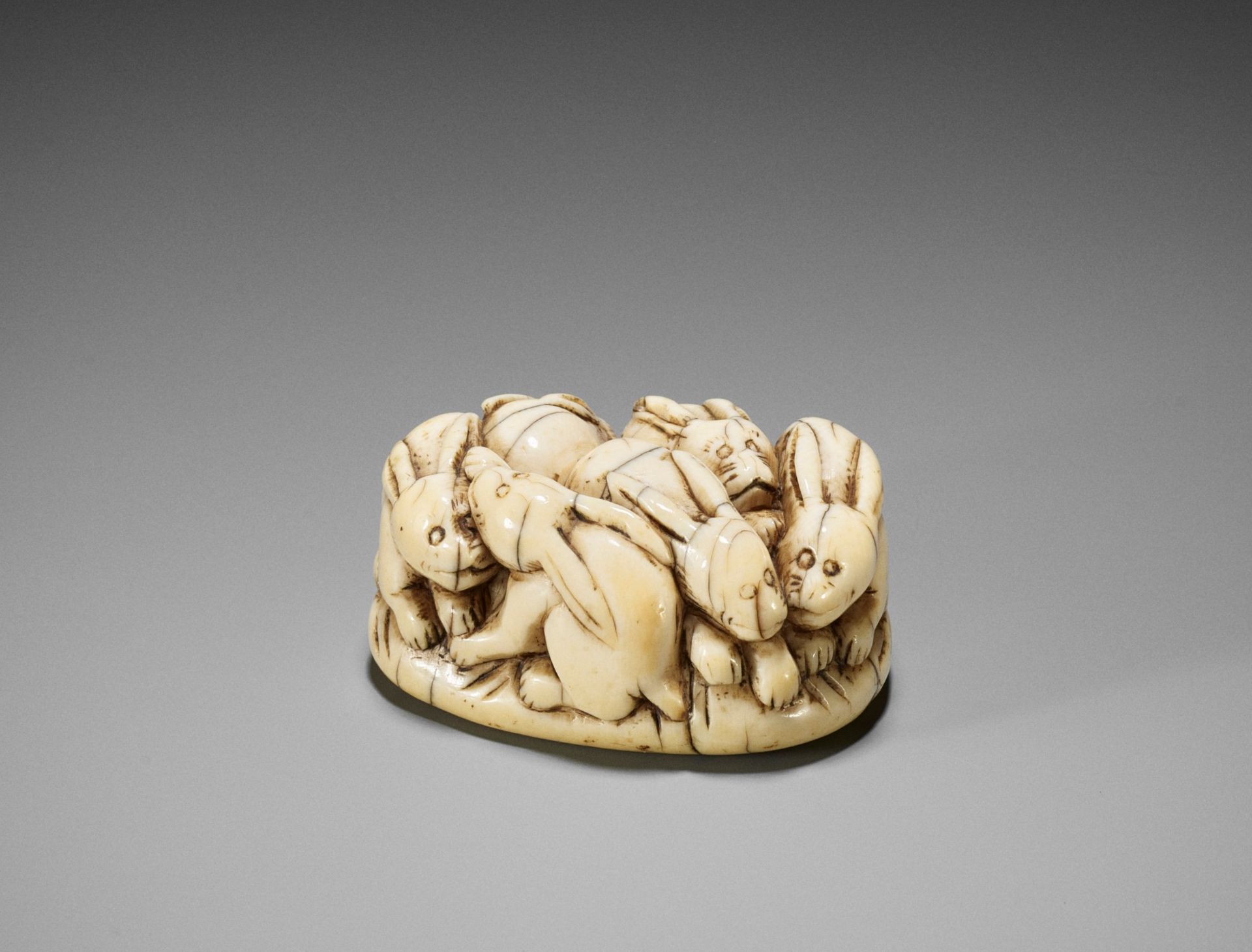 A RARE IVORY NETSUKE OF A PILE OF RABBITS