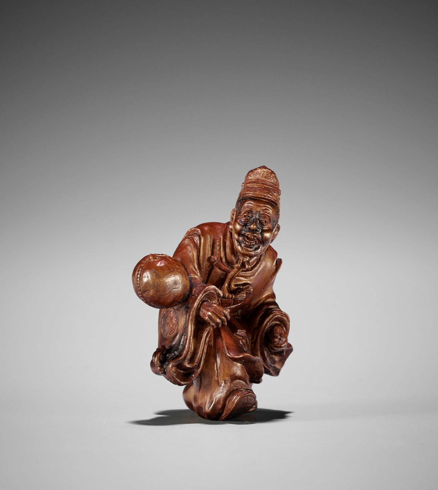 SEIHO: A FINE STAINED BOXWOOD NETSUKE OF A KEMARI PLAYER