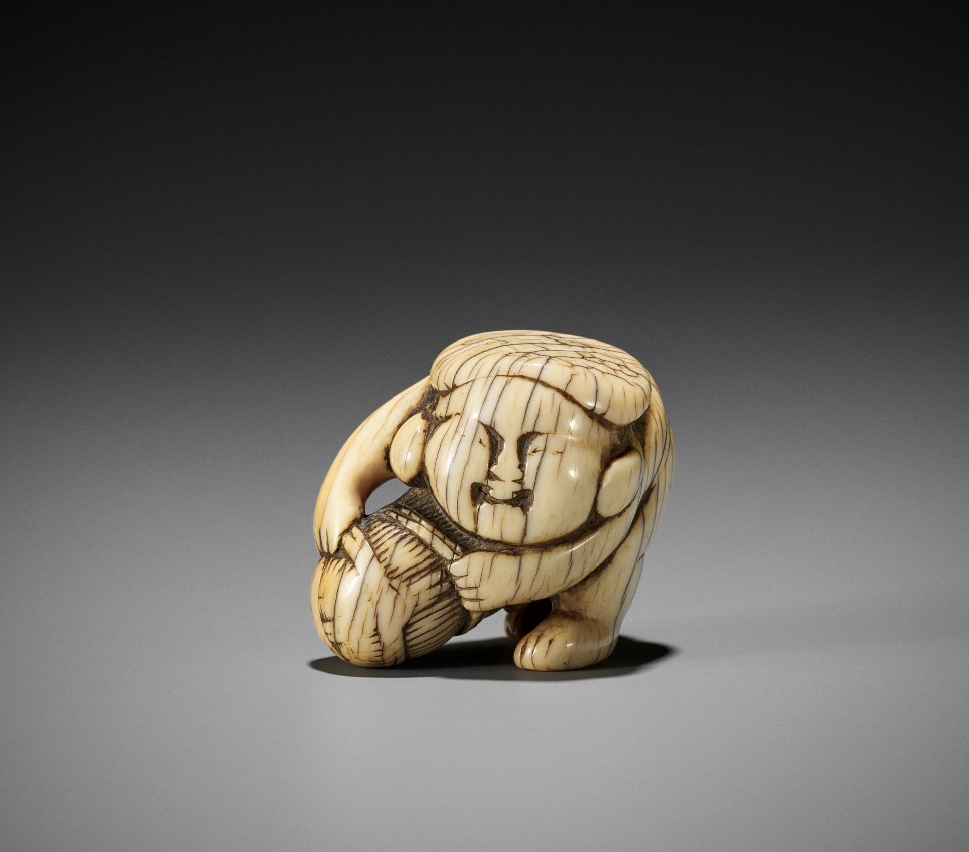 AN IVORY SHUNGA NETSUKE OF DAIKOKU WITH RICE BALE