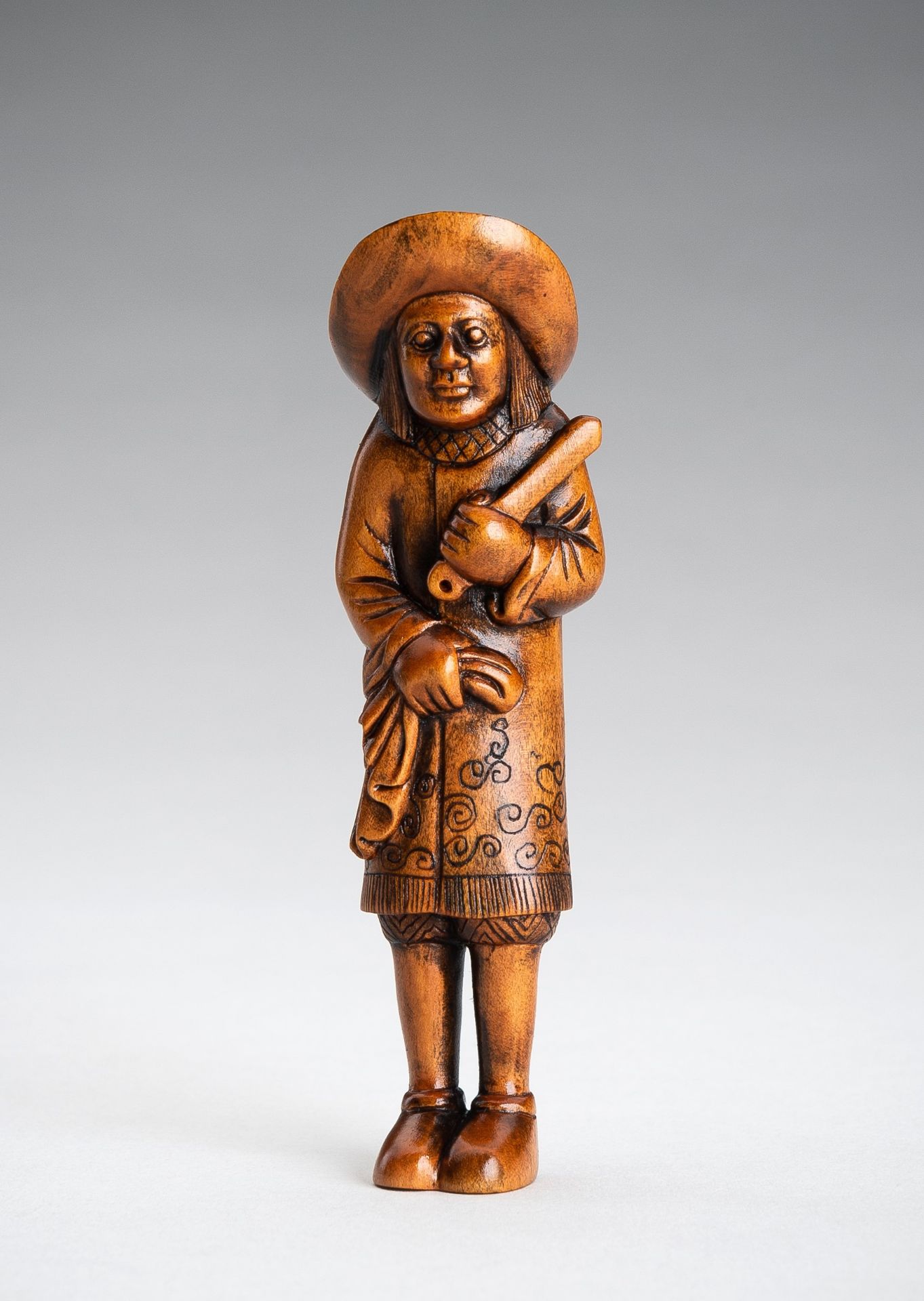 A BOXWOOD NETSUKE OF A DUTCHMAN AS A BARBER